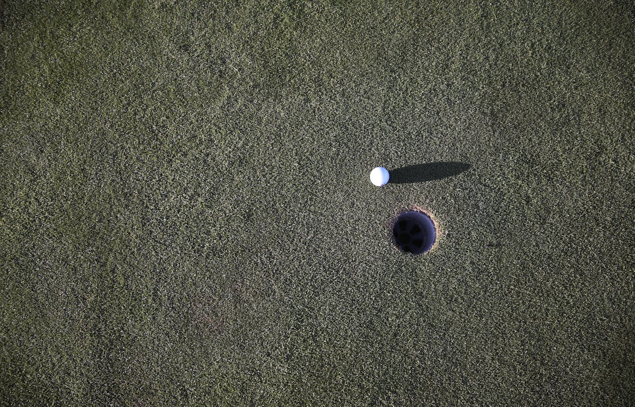 Close-up shot of a golf ball near the hole on a manicured golf course green.